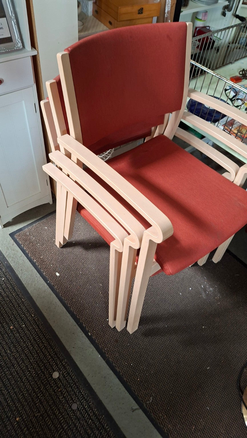 Vier stapelbare Brunner Armlehnenstühle mit roter Polsterung und hellem Holzgestell