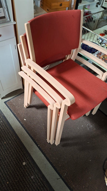 Vier stapelbare Brunner Armlehnenstühle mit roter Polsterung und hellem Holzgestell